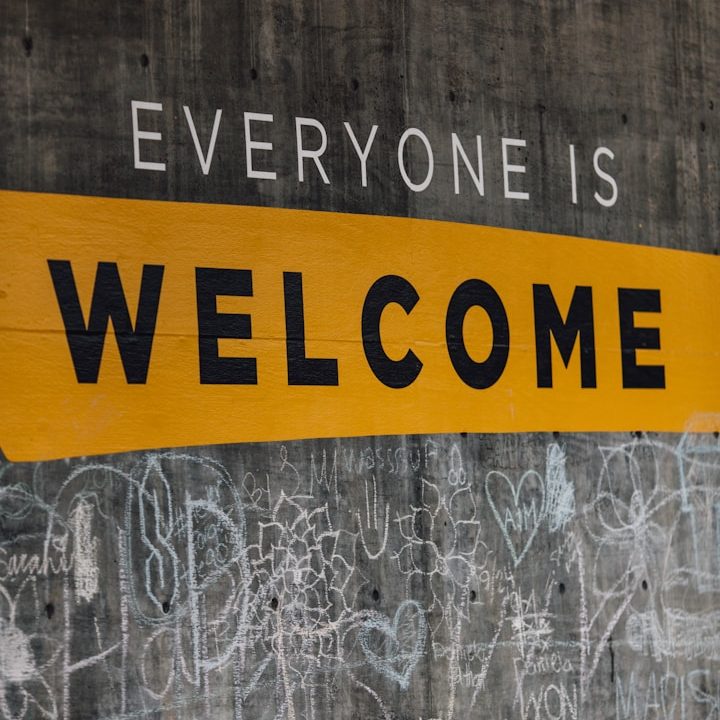 Mural with the text "Everyone is Welcome" on a grey wall.